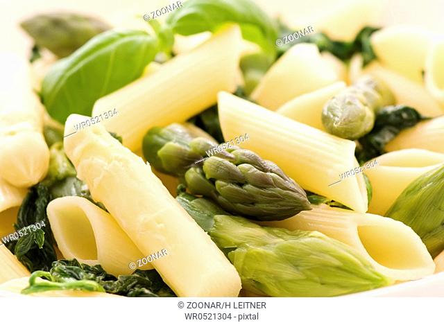 Italian noodles with asparagus spears as closeup on a white plate