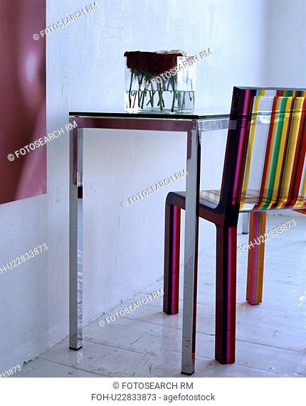 Close-up of multi-coloured striped perspex chair with metal table