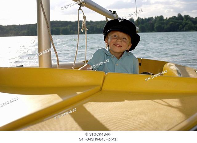 Little boy peering over the edge of a plastic boat