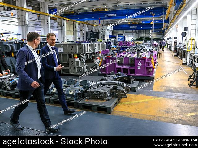 03 April 2023, Saxony, Schwarzenberg: Michael Kretschmer (CDU, r), Minister President of Saxony, walks through the factory halls of Porsche Werkzeugbau GmbH...