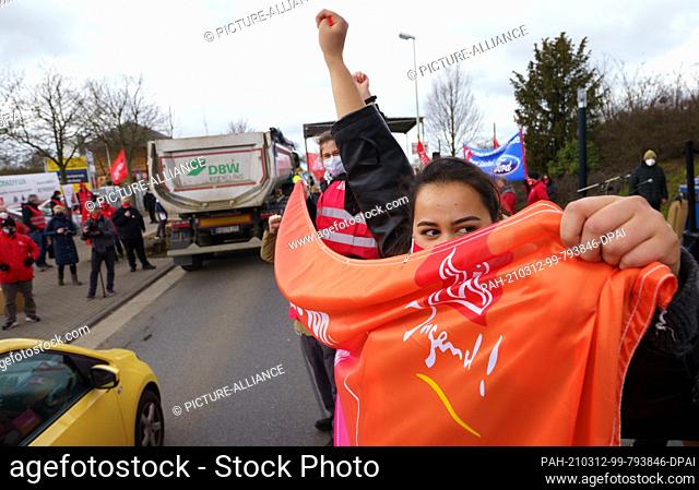 12 March 2021, Rhineland-Palatinate, Mainz: Rally participants demonstrate with raised fists. IG Metall has called on its members to go on warning strike