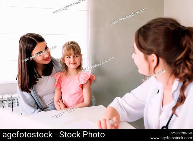 Mother or sister with small little girl visiting hospital for the family doctor visit in the clinic. High quality photo