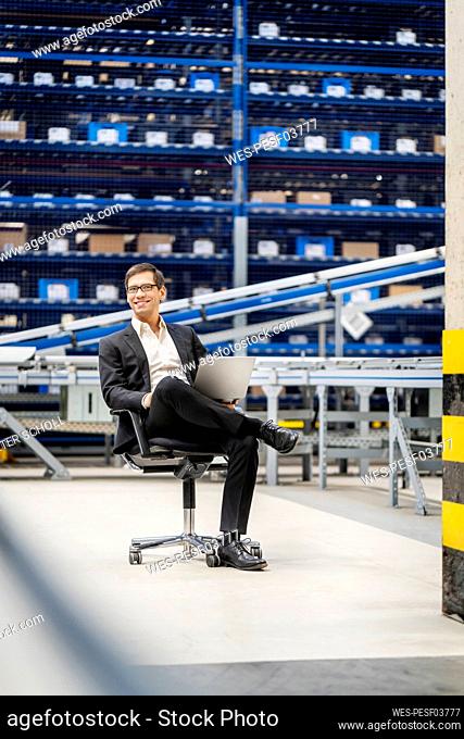Mature businessman sitting on chair at factory