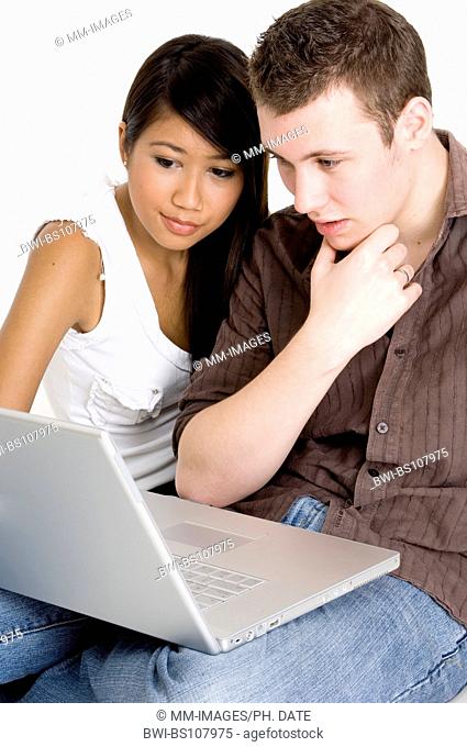 A young couple in front of a laptop computer