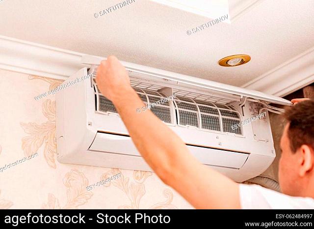 the repairman cleans or repairs the air conditioner in the house. annual split system maintenance. preparation for the hot season