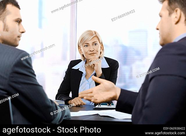 Mid-adult businesswoman concentrating at meeting on businessmen's discussion