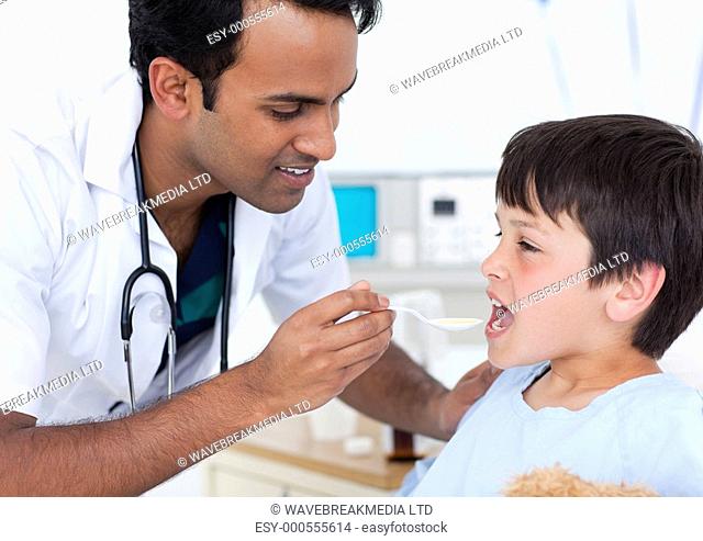 Attractive doctor giving medicine to a little boy at the hospital