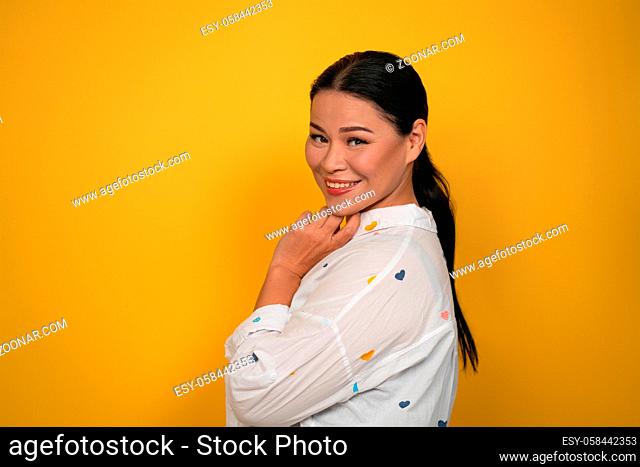 Charming Asian woman smiling at camera. Cute middle aged female model cutout on yellow background. Copy space