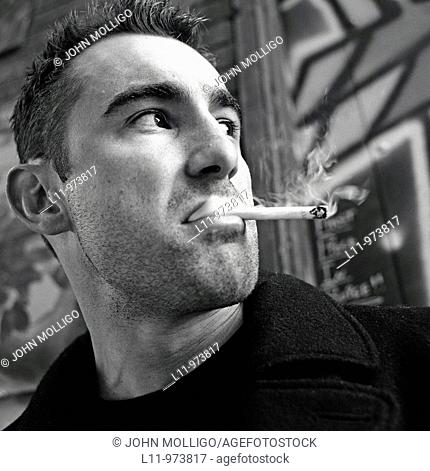 Close-up of man in alley, smoking a cigarette
