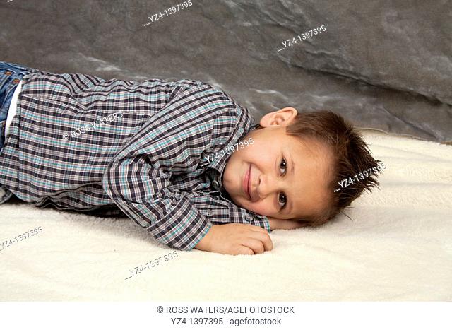 A boy smiling and laying down indoors