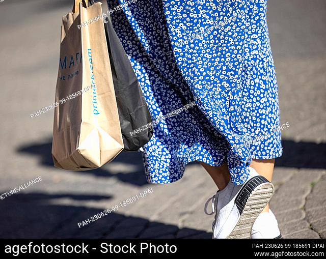 PRODUCTION - 24 June 2023, North Rhine-Westphalia, Cologne: A woman carries a paper bag with the logo of the department store chain Primark in Cologne's...