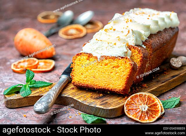 Sliced spicy carrot cake with cottage cheese and cream on a wooden serving board, selective focus