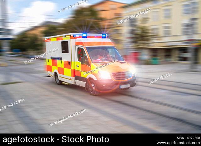 an ambulance drives through the city with flashing lights and high speed