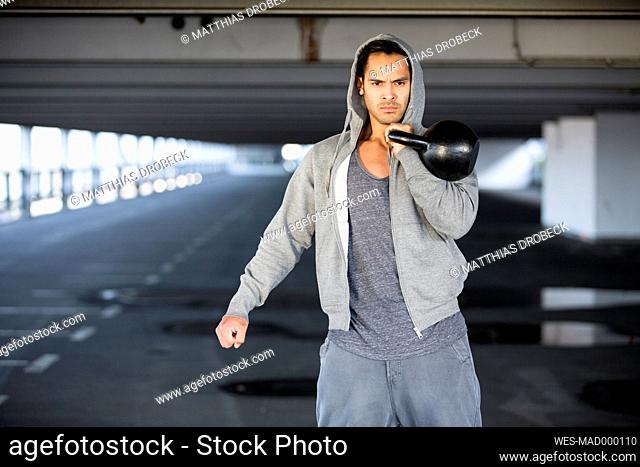 Man wearing hooded jacket training with kettlebell