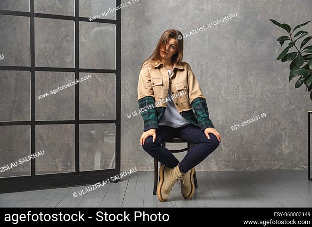Young caucasian millennial woman stylishly dressed in demi season style sitting indoors