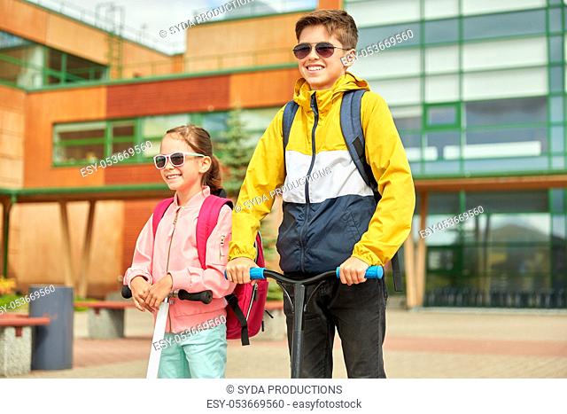 happy school children with backpacks and scooters