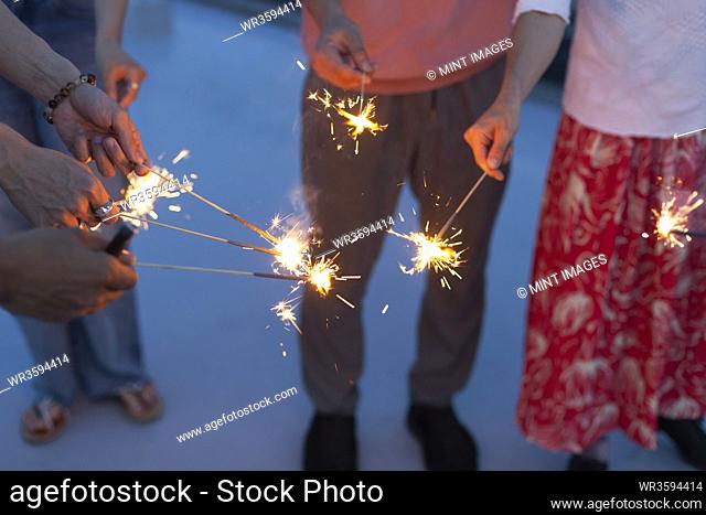 Group of young men and women with sparklers on a rooftop in an urban setting