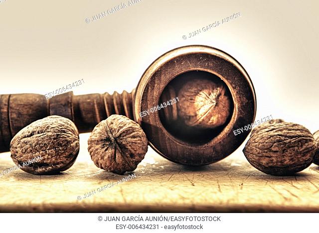 Walnuts and old wooden nutcracker isolated over white background, placed on wooden surface