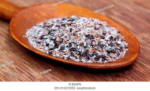 Medicinal herbs isabgul and basil seeds on a wooden spoon on wooden surface