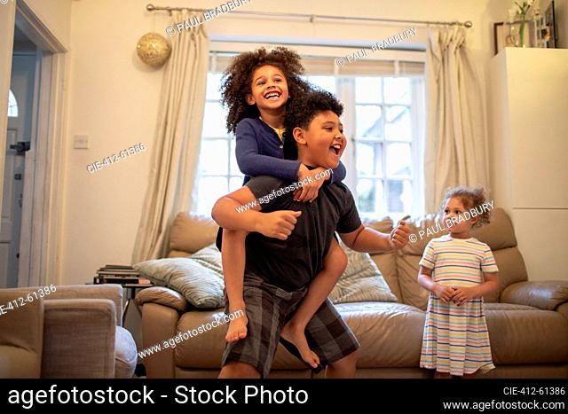 Happy boy piggybacking sister in living room