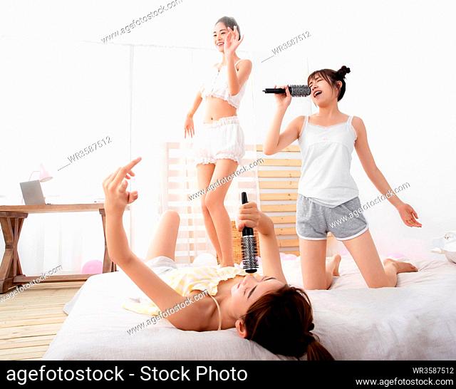 Girlfriends singing and dancing in the bedroom