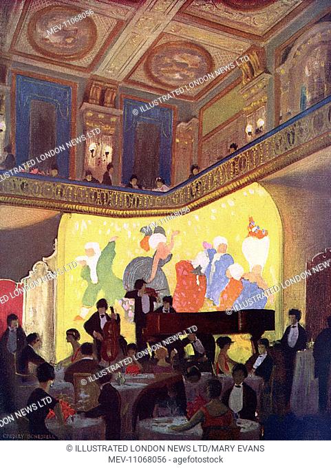 View of the interior of the Trocadero in London, with diners at tables and a band playing against a mural