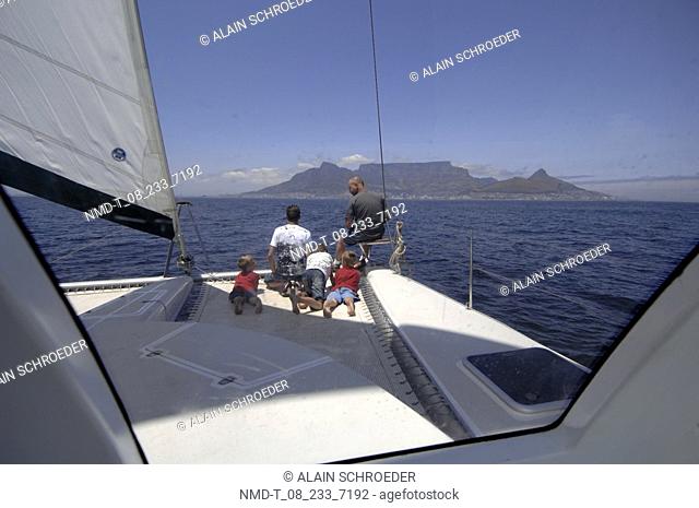 Rear view of two men with three boys on a sailboat, Table Mountain, Cape Town, Western Cape Province, South Africa