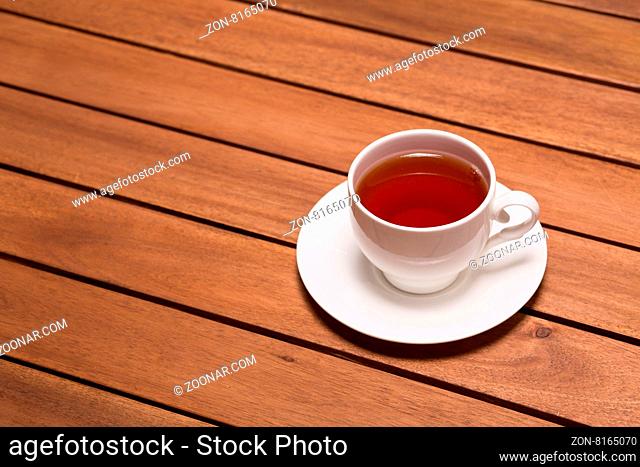 A top view of a cup of green tea on the wooden table in restaurant of cafe. Delicious tea pored in white cup represented on white saucer