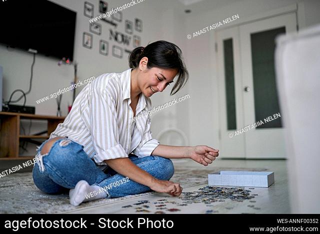 Happy woman playing puzzle at home