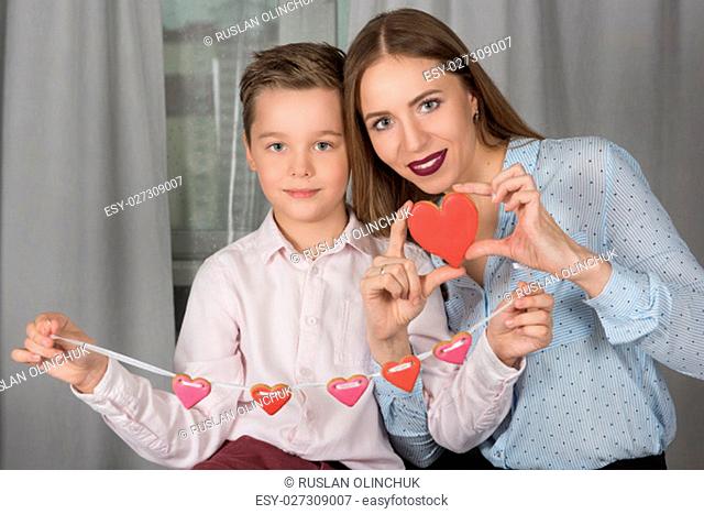 Happy Valentines Day or Mother day. Young boy spend time with her mum and celebrate with gingerbread heart cookies on a stick