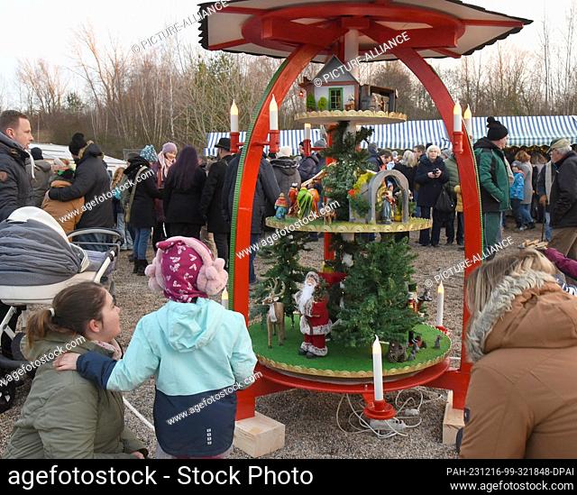 16 December 2023, Saxony, Schkeuditz: Visitors look at a small Christmas pyramid at the Victorian Christmas market on Biedermeierstrand in Hayna near Leipzig