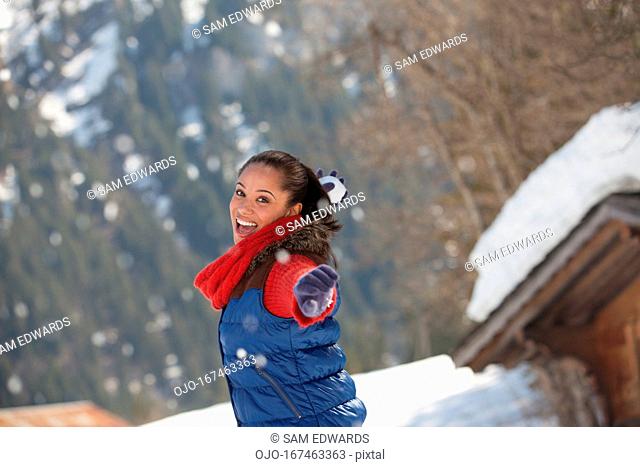 Portrait of smiling woman throwing snowball