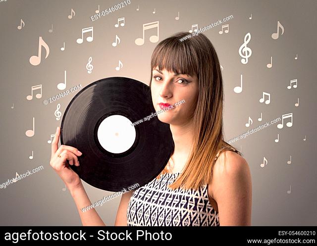 Young lady holding vinyl record on a brown background with musical notes behind her