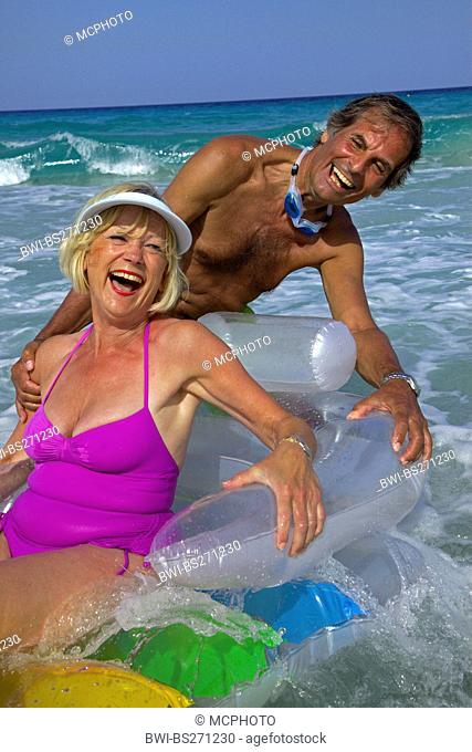 elderly couple splashing in the sea with air bed, Balearen, Ibiza