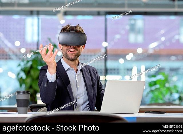 Businessman with VR googles gesturing in office