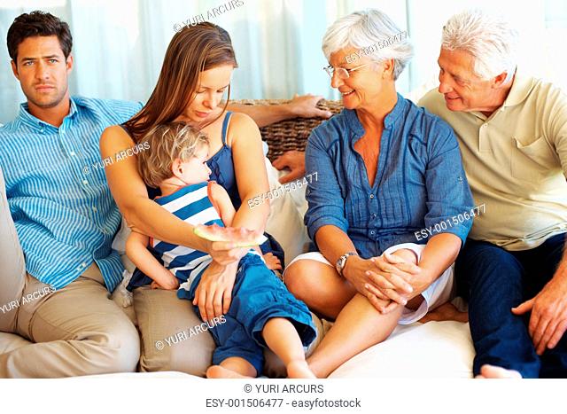Family sitting together on sofa with mother hugging kid