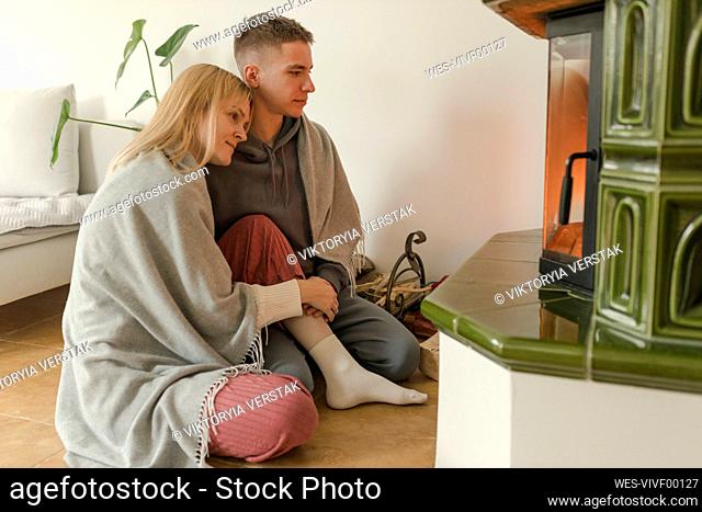 Young couple sitting together in front of fireplace at home