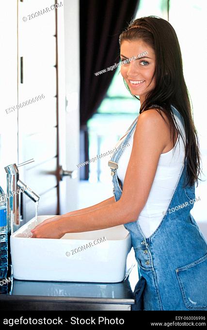 Side view of beautiful young woman in bathroom washing hands