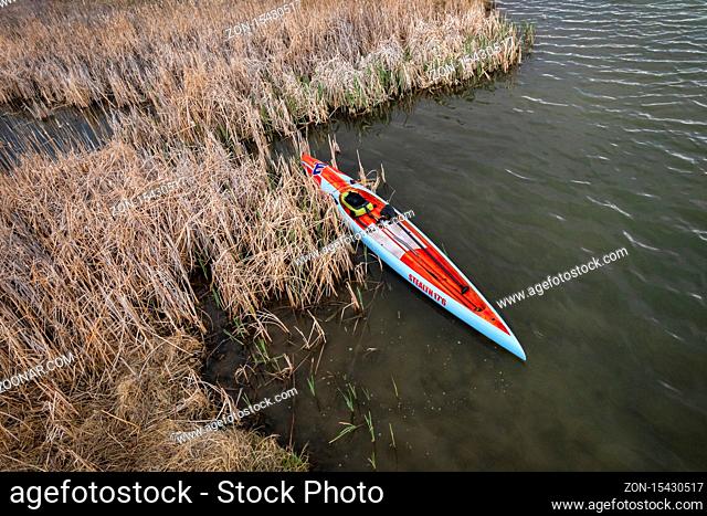 Fort Collins, CO, USA - May 1, 2020: Aerial view of a long racing flatwater stand up paddleboard (Mistral Stealth) on a calm lake after paddling workout in...