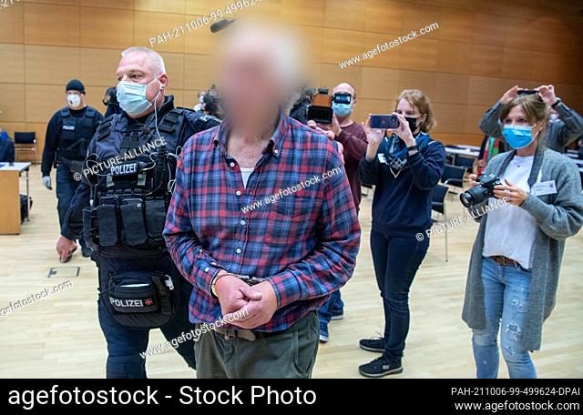 06 October 2021, Hessen, Hanau: The defendant is led into the courtroom by a police officer. The man is the father of the assassin of Hanau