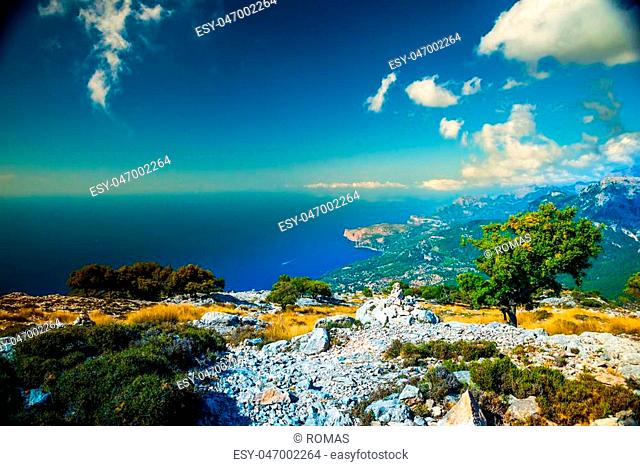 Beautiful landscape view of rocky mountains and clouds on the western part of Mallorca island, Spain. Tramuntana mountains with blue sea in background