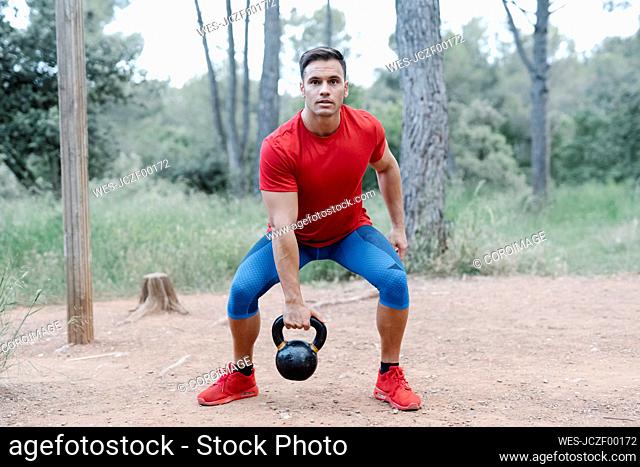 Young athletic man with dumbbell in the woods