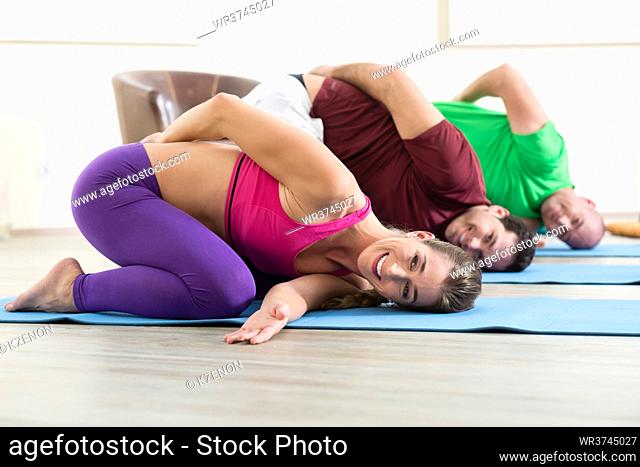 Smiling two man and woman practicing yoga in class