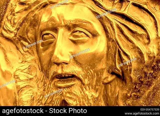 Golden bas-relief of Jesus crowned with thorns. High golden relief face of Jesus Christ with crown of thorns
