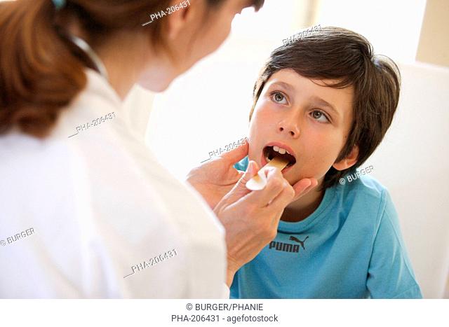 Doctor examining the throat of a 9 years old boy