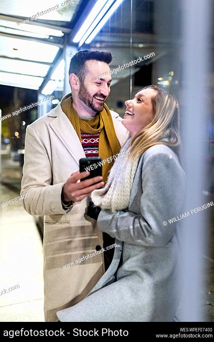 Happy man and woman standing with mobile phone