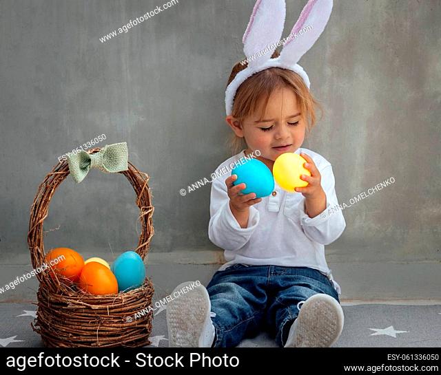 Portrait of Cute Little Baby Boy with Nice Rabbit Ears. Basket Full of Colorful Eggs. Happy Easter Celebration