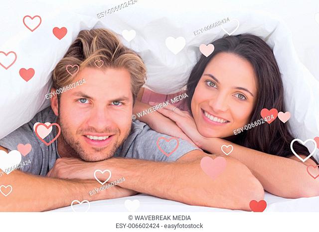 Composite image of beautiful couple smiling under the cover