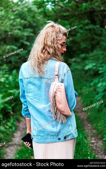 Fashion young beautiful blonde woman with a bag. Vogue style
