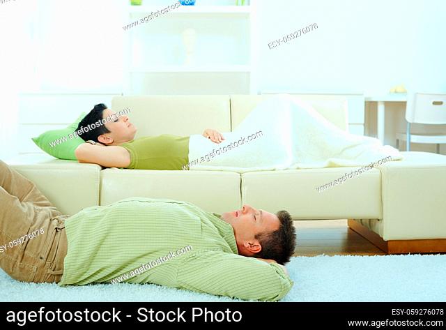 Couple sleeping at home on sofa and on floor